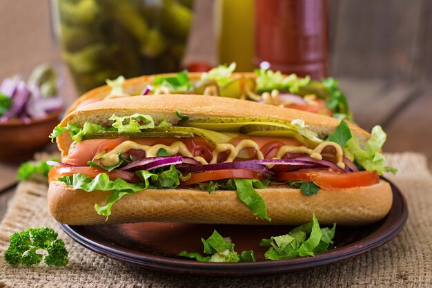 Hot-Dog avec cornichons, tomate et laitue sur une surface en bois