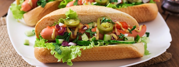 Photo hot-dog avec du piment jalapeno, du tomate, du concombre et de la laitue sur fond de bois
