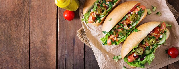 Photo hot-dog avec du piment jalapeno, du tomate, du concombre et de la laitue sur fond de bois