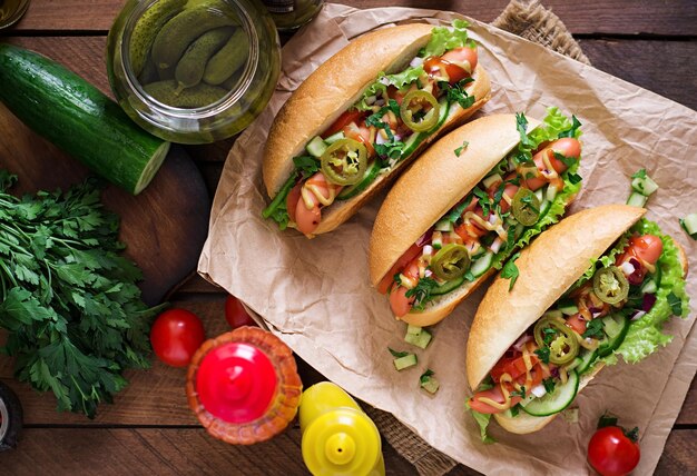 Photo hot-dog avec du piment jalapeno, du tomate, du concombre et de la laitue sur fond de bois