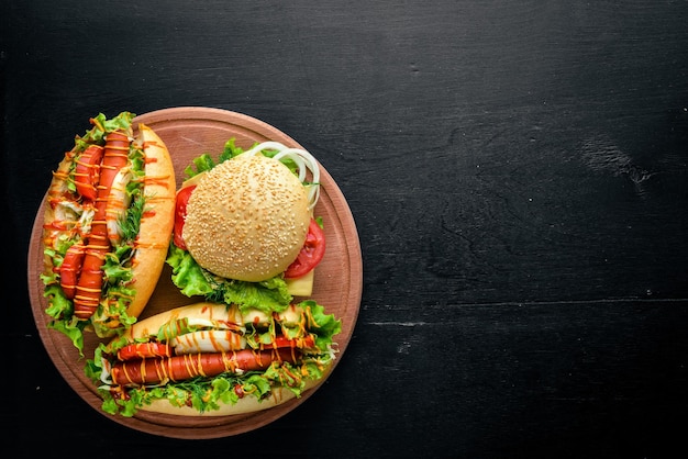 Hot-dog et hamburger avec viande au fromage et légumes verts sur fond en bois Vue de dessus Espace libre