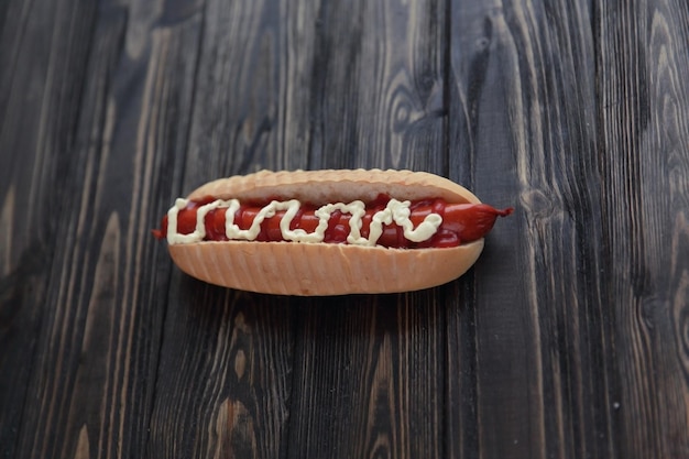 Hot-dog avec saucisse fumée et mayonnaise sur fond de bois