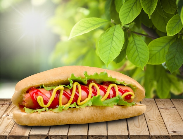 Hot-dog savoureux avec de la moutarde sur une table en bois