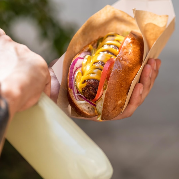 Hot-dog traditionnel avec une saucisse de Francfort fumée sur un petit pain frais garni de moutarde et servi avec de la laitue, de la tomate et de l'oignon sur un fond de pierre grise