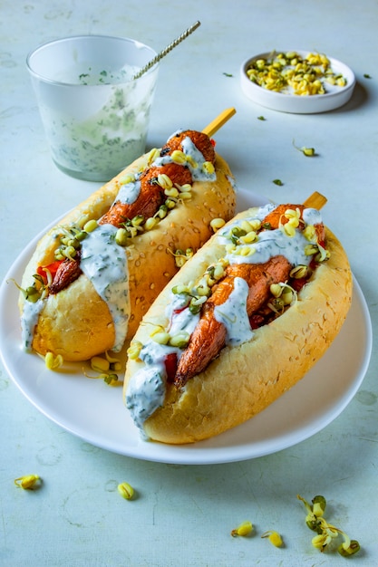 Hot-dog végétalien aux carottes avec grains germés et sauce à la crème. Assiette blanche avec de la nourriture de rue végétarienne. Concept de repas sans viande à base de plantes saines.