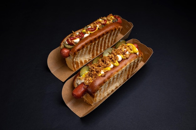 Hot-dogs dans des assiettes en carton avec saucisses et sauce