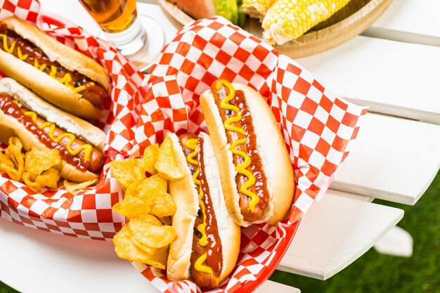 Hot-dogs grillés avec de la moutarde et du ketchup sur la table avec de la bière pression.