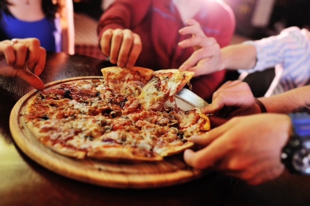 Photo hot pizza gros plan sur une table à l'arrière-plan d'un groupe ou d'une société entre amis