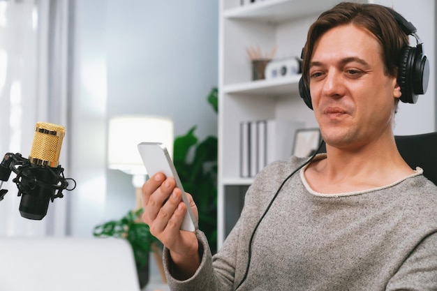 Photo hôte de la chaîne dans le radiodiffuseur en utilisant un smartphone pour discuter avec l'auditeur pecuniary