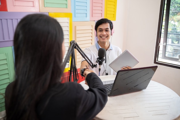 Un hôte masculin serre la main d'une invitée lors d'un podcast