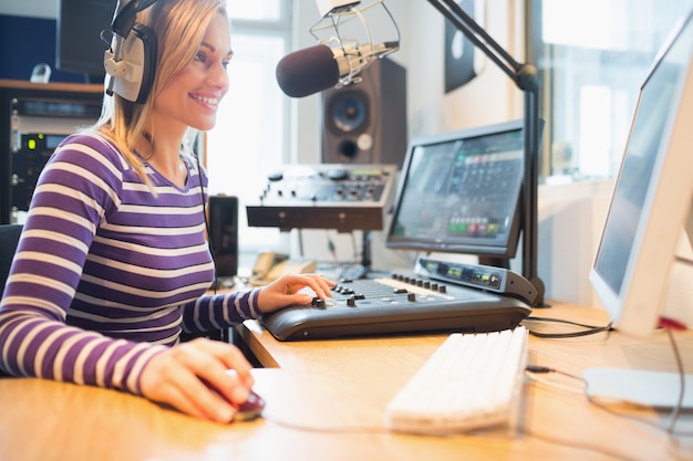 Hôte de radio féminin utilisant un ordinateur pendant la diffusion