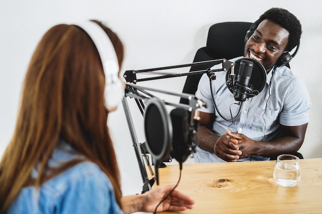 Hôtes ayant une session de podcast ensemble - Un orateur africain fait une interview pendant la diffusion en direct - L'accent est mis sur le microphone