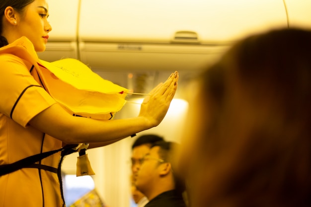 Photo hôtesse de l'air indique aux passagers comment utiliser un gilet de sauvetage à bord