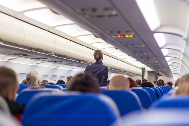 Hôtesse de l'air marchant dans l'allée d'un avion commercial