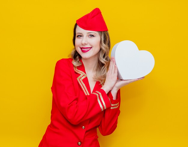 hôtesse de l&#39;air portant un uniforme rouge avec boîte de gfit de vacances en forme de coeur