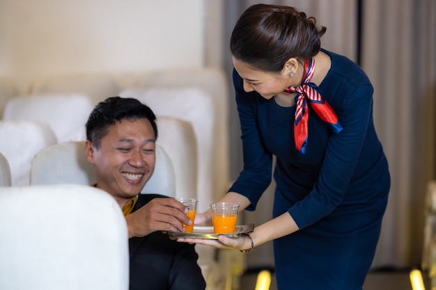 Hôtesse de l'air servant, hôtesse de l'air asiatique servant des boissons aux passagers de l'avion, équipage de cabine ou hôtesse de l'air travaillant dans l'avion.