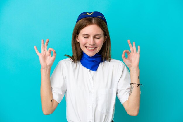 Hôtesse de l'avion anglaise femme isolée sur fond bleu dans une pose zen