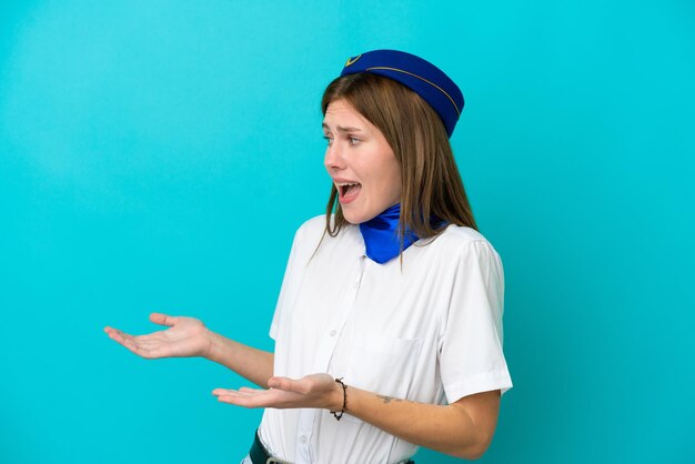 Hôtesse de l'avion femme anglaise isolée sur fond bleu avec une expression faciale surprise