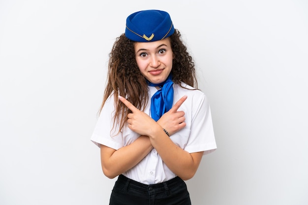 Hôtesse de l'avion femme arabe isolée sur fond blanc pointant vers les latéraux ayant des doutes