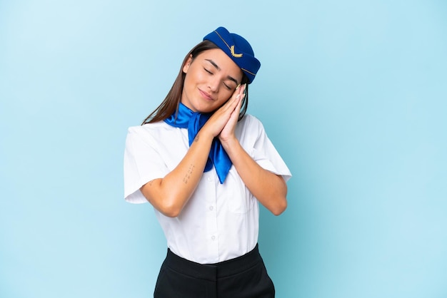 Hôtesse de l'avion femme caucasienne isolée sur fond bleu faisant un geste de sommeil dans une expression dorable