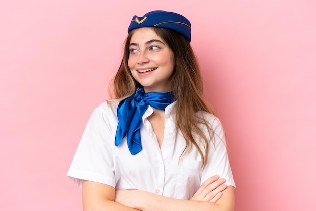 Hôtesse de l'avion femme caucasienne isolée sur fond rose avec les bras croisés et heureux