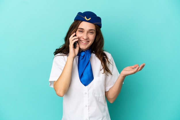 Hôtesse d'avion femme isolée sur fond bleu en gardant une conversation avec le téléphone portable avec quelqu'un