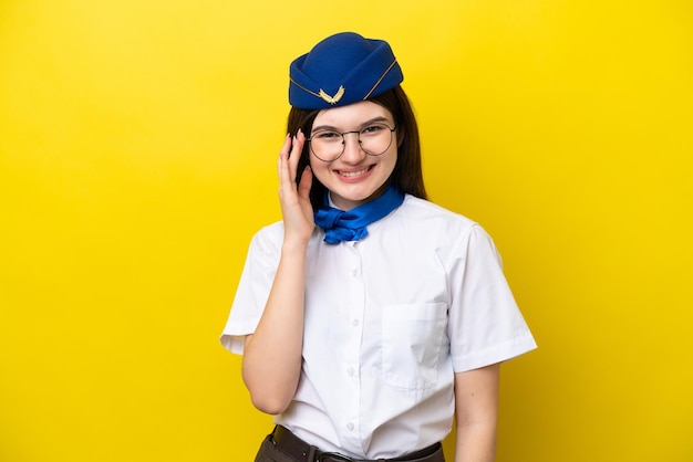 Hôtesse de l'avion femme russe isolée sur fond jaune avec des lunettes et heureux