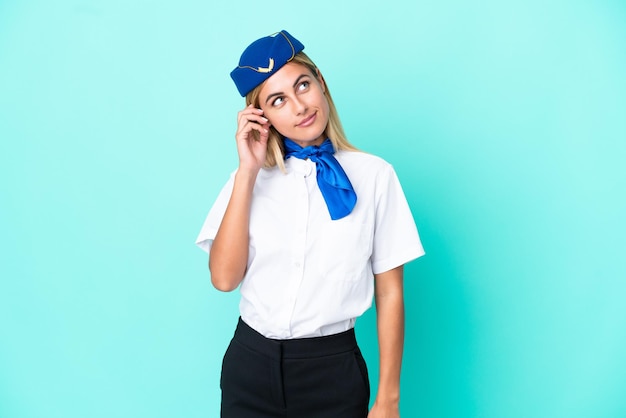 Hôtesse d'avion femme uruguayenne isolée sur fond bleu en pensant à une idée