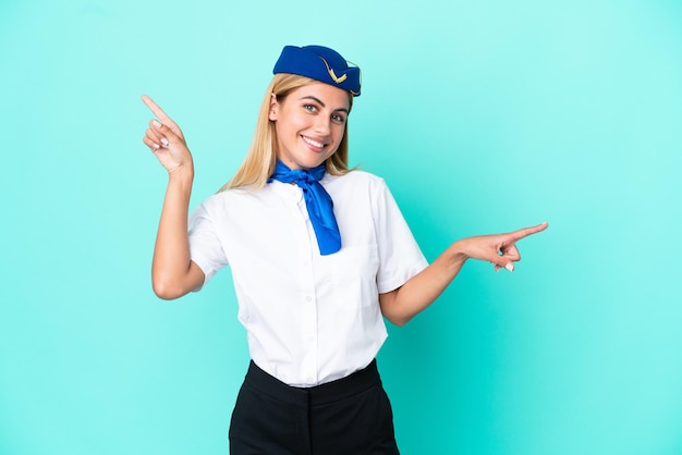 Hôtesse de l'avion femme uruguayenne isolée sur fond bleu pointant le doigt vers les latéraux et heureux