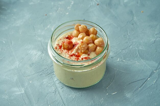 Houmous classique dans un pot sur fond gris