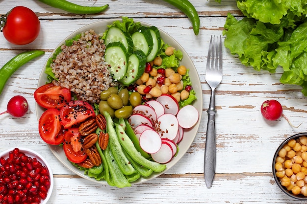 Houmous dans un bol, bâtonnets de légumes, pois chiches, olives.