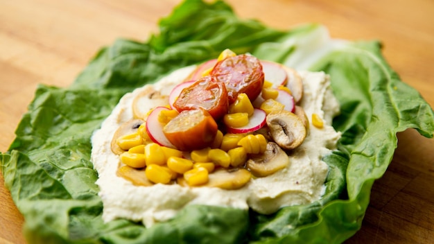 Houmous sur une feuille de salade avec maïs et radis