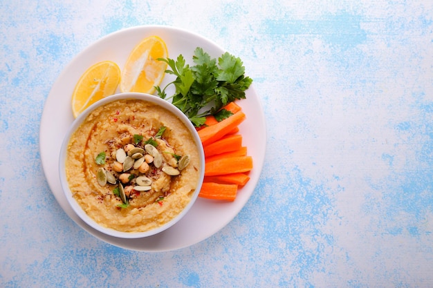 Houmous sur fond bleu avec carottes, citron et épices avec place pour le texte