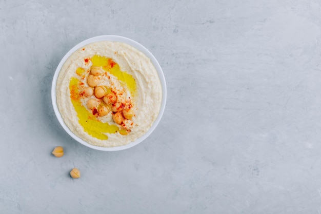 Houmous à l'huile d'olive et au paprika dans un bol sur un fond de béton gris