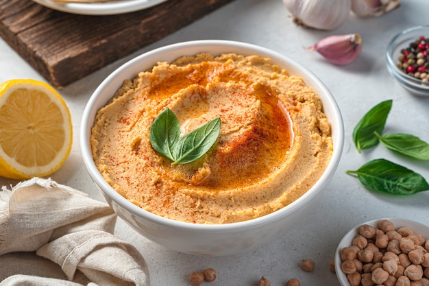 Houmous à l'huile d'olive et au paprika en gros plan sur fond gris avec des ingrédients