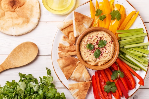 Houmous maison sain avec un assortiment de légumes frais et de pain pita.