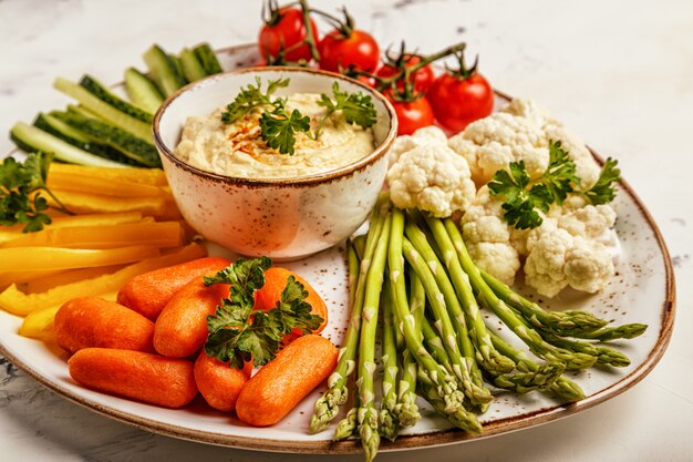 Houmous maison sain avec un assortiment de légumes frais.