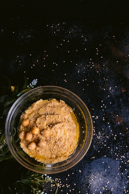 Houmous de pois chiche au sésame dans un bol en verre sur une table en bois. Nourriture végétalienne