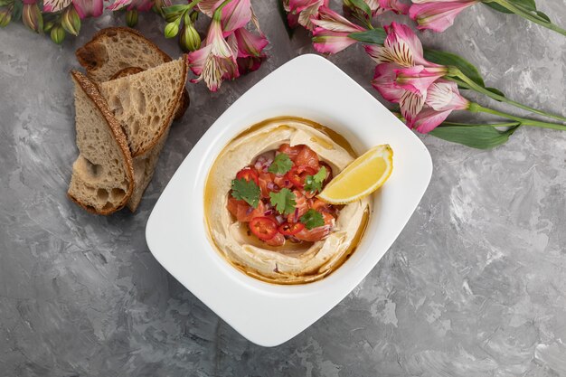 Houmous avec une tranche de citron sur une assiette blanche