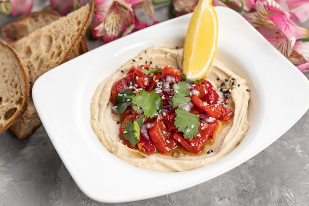 Houmous avec une tranche de citron sur une assiette blanche