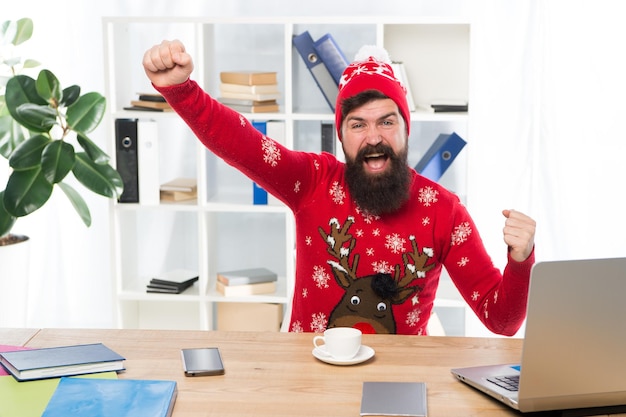 Photo hourra pour les vacances joyeux hipster fêter les vacances au bureau un homme barbu sourit avec un look d'hiver joyeuses fêtes vacances d'hiver ou vacances saison des fêtes noël et nouvel an