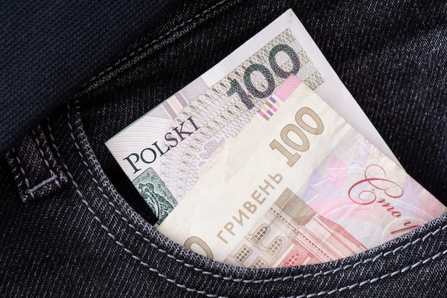 La hryvnia ukrainienne et le zloty polonais dépassent de la poche du jean en gros plan Les billets de banque des pays voisins Le concept d'unité et d'assistance mutuelle de l'Ukraine et de la Pologne L'échange d'argent