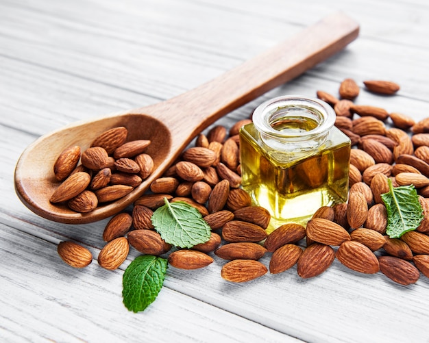 Huile d'amande et amandes sur une surface en bois blanche