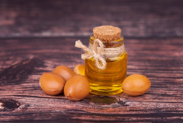 Huile d'argan sur fond de bois Noix et graines d'argan pour produits cosmétiques et de beauté Fruit d'arganier naturel du Maroc