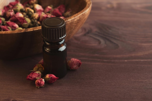 Huile aromatique à l'essentiel de rose sur fond bois foncé. Spa, aromathérapie, soins esthétiques