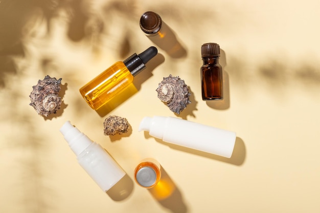 Huile de bronzage Produits cosmétiques à côté de coquillages dans les rayons du soleil sur fond rose Cosmétiques de protection solaire