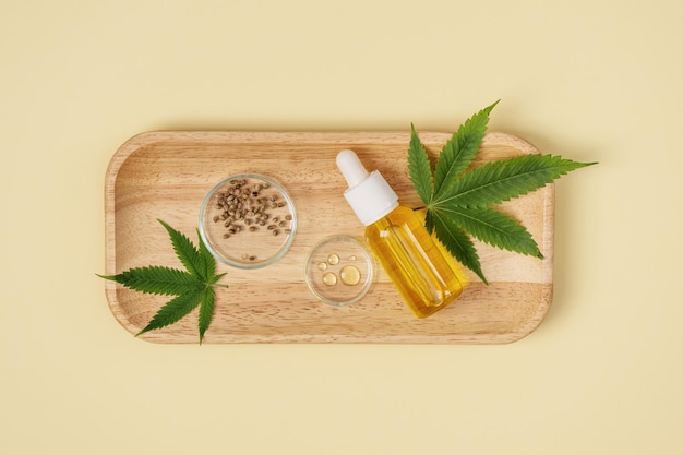 Huile de cannabis et feuilles et graines de chanvre sur fond jaune vue de dessus Huile de CBD de chanvre dans une bouteille et graines de chanvre pour les soins de la peau