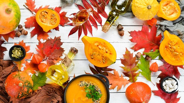 Huile de citrouille et citrouilles Légumes d'automne à plat Sur un fond en bois blanc Vue de dessus Espace libre pour votre texte