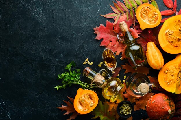 Huile de citrouille et citrouilles Légumes d'automne à plat Sur fond de pierre noire Vue de dessus Espace libre pour votre texte