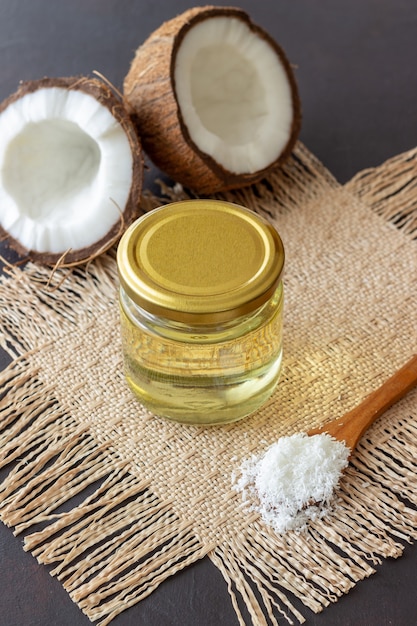 L'huile de coco dans un pot et les noix de coco fraîches sur une surface sombre. Cosmétiques naturels.